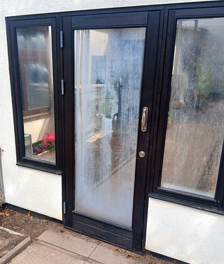 A black aluminium door and side panels, the glass clouded white with condensation trapped inside the sealed units
