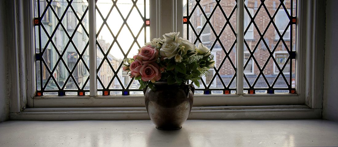 A leaded light window with diamond panes and small squares of coloured glass