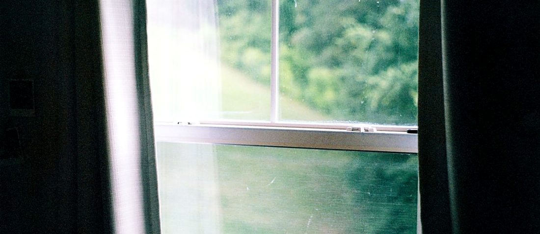 A window open onto greenery, curtain to one side