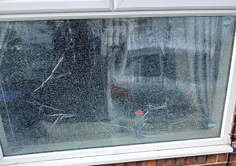 A toughened pane that has shattered into thousands of small blunt granules while holding its shape in the frame